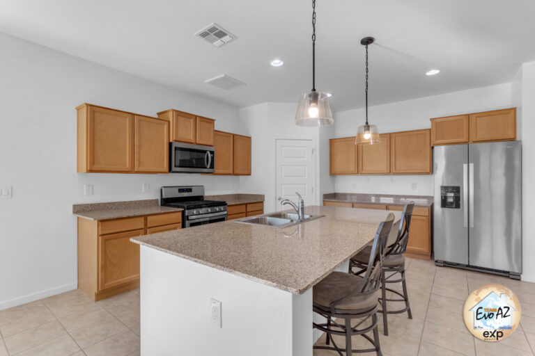 Kitchen with island in a Maricopa AZ single-level home with large garage, featuring granite countertops and modern lighting