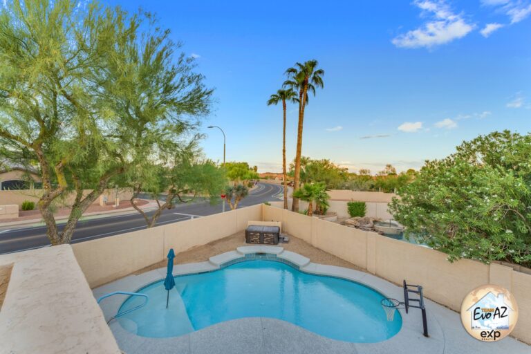Private backyard with swimming pool, palm trees, and desert landscaping at an Ahwatukee property