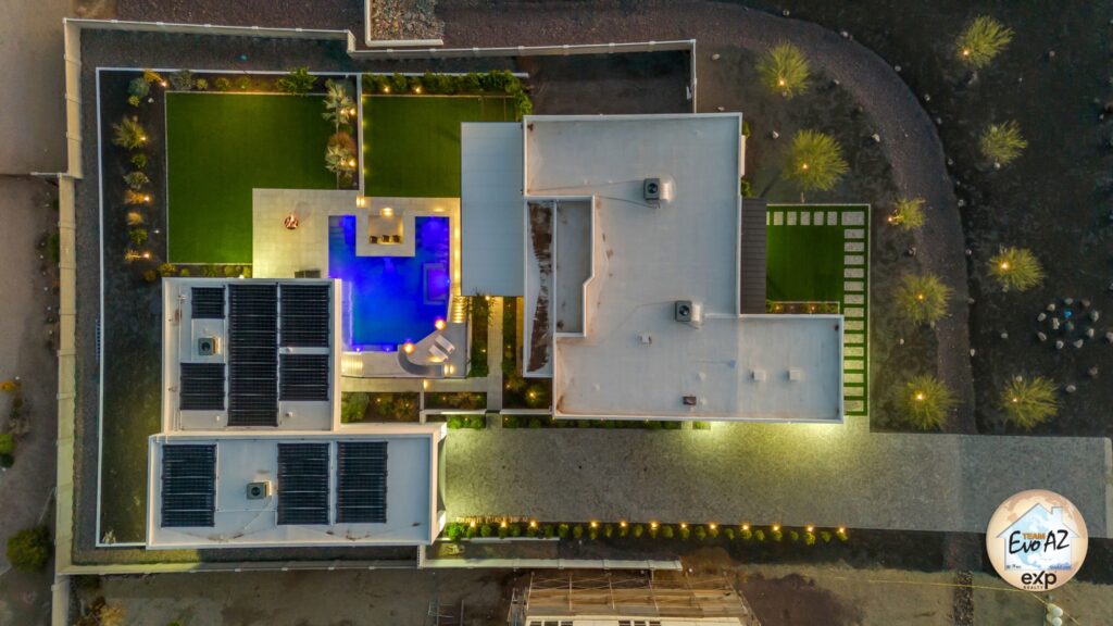 Drone view of a custom-built home on a full acre in Surprise Arizona with illuminated pool and outdoor living