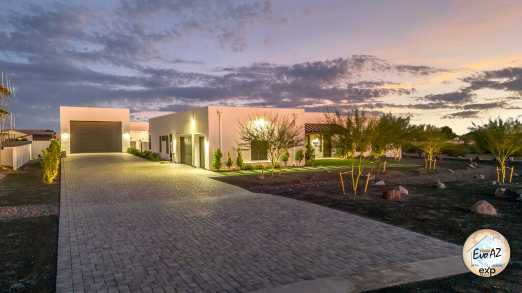 Twilight exterior of a custom single-level home in Surprise Arizona with expansive driveway and desert surroundings